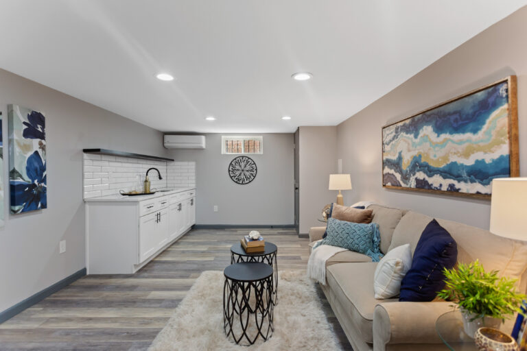 Cozy living room showcasing a couch, coffee table, and wet bar, part of a Veteran Built Homes basement remodel.