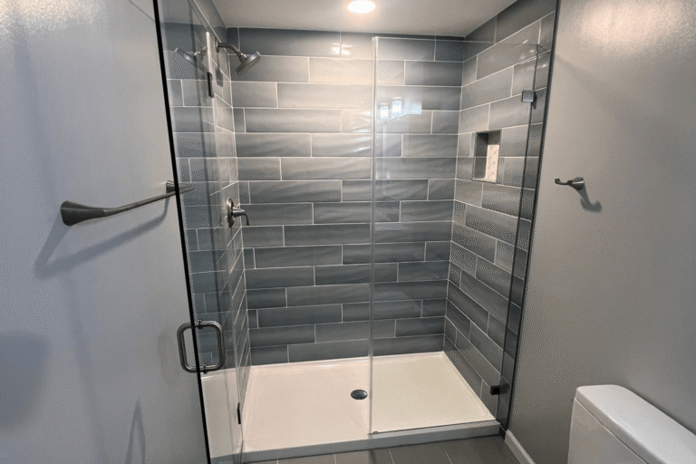 Walk-in shower remodel in Northern Virginia by Veteran Built Homes featuring large-format matte gray subway tile, glass shower enclosure, built-in shampoo niche, and brushed nickel fixtures for a sleek and modern bathroom upgrade.