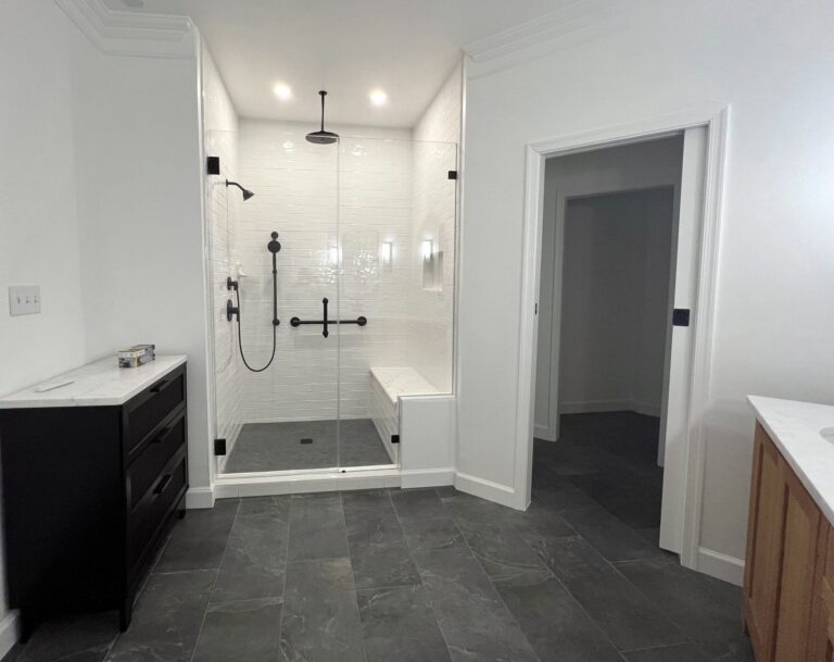 Accessible bathroom with a shower, sink, and toilet, including handrails and 36-inch wide doors for aging in place.