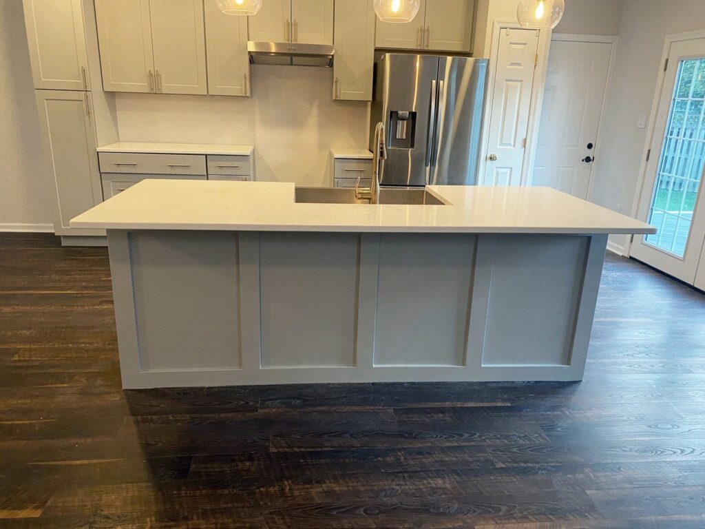 A wheelchair accessible kitchen featuring a white island, hardwood floors, and ample space between the island and refrigerator.
