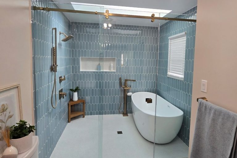 Modern luxury bathroom remodel in Alexandria, VA, featuring a wet room design with blue scalloped wall tile, a freestanding soaking tub, gold hardware, and a skylight, completed by Veteran Built Homes.