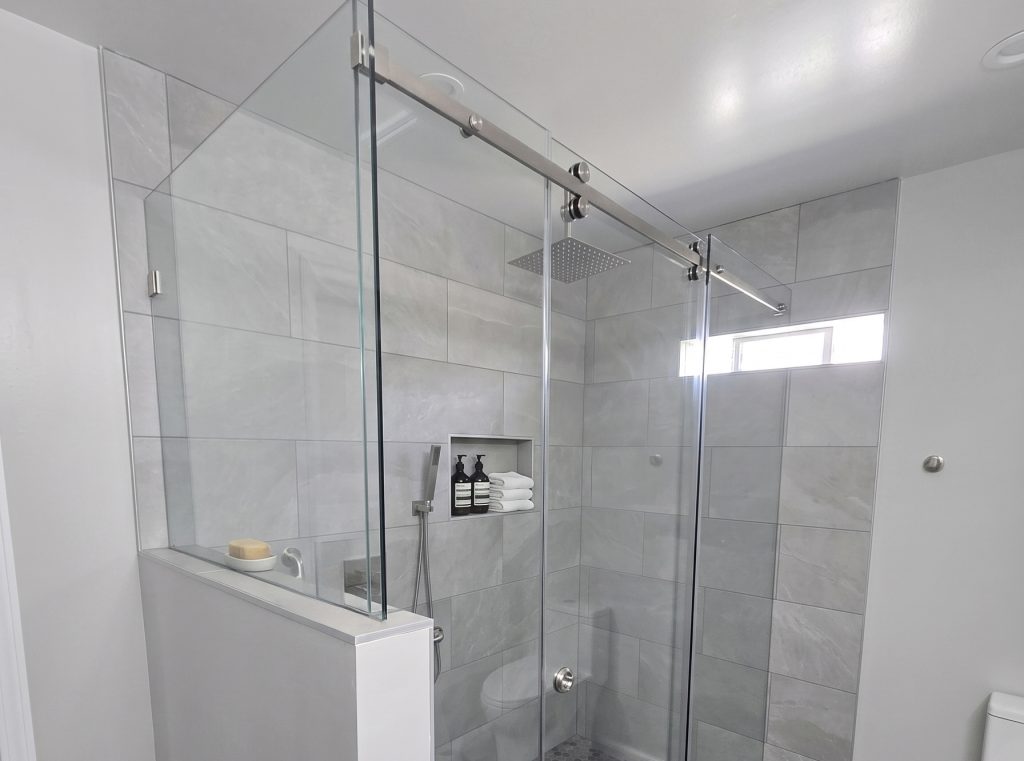 glass walled shower with grey tile and silver accents